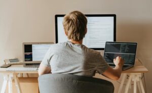 Person working at a desk with three computer screens